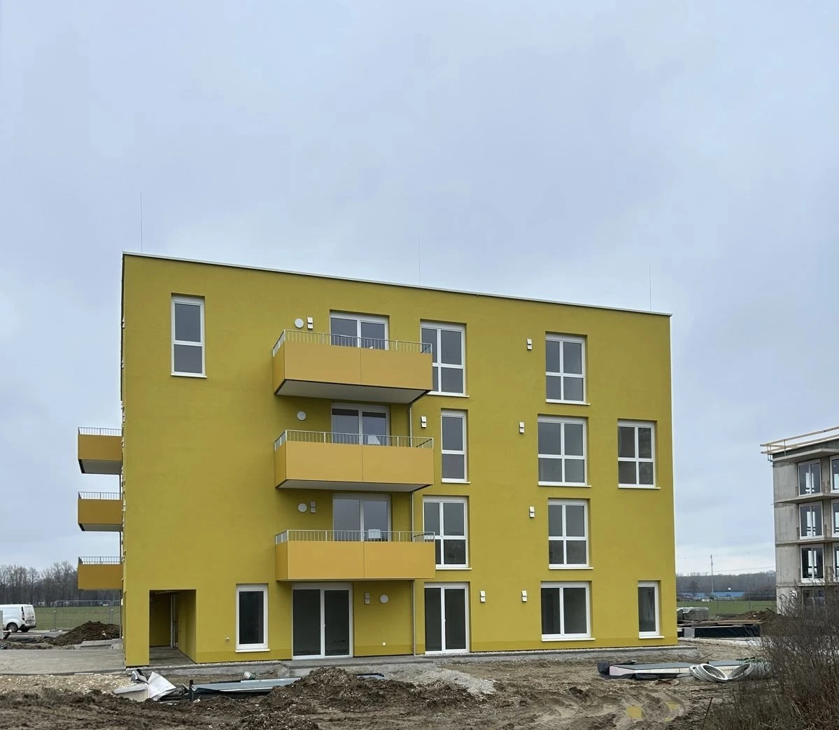Wohngebäude mit gelber Fassade und montierten Fenstern